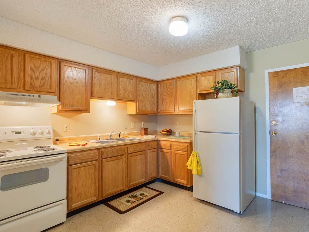 Village Square Apartment kitchen with white appliances and wooden cabinets