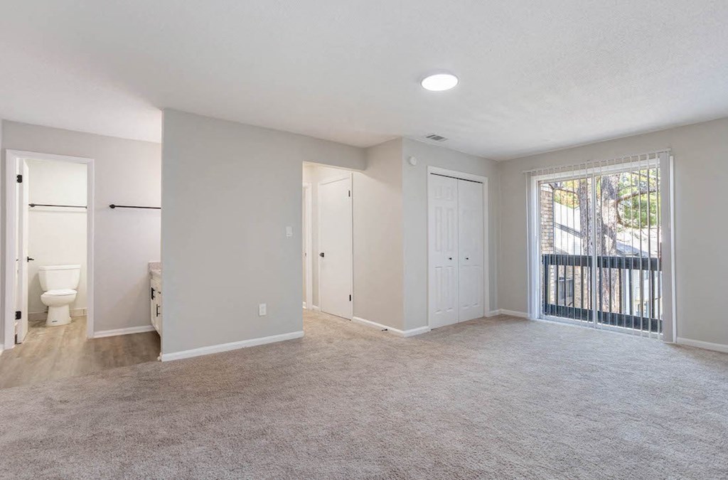 a bedroom with sliding glass doors leading to a deck, and a bathroom with a sink vanity and toilet