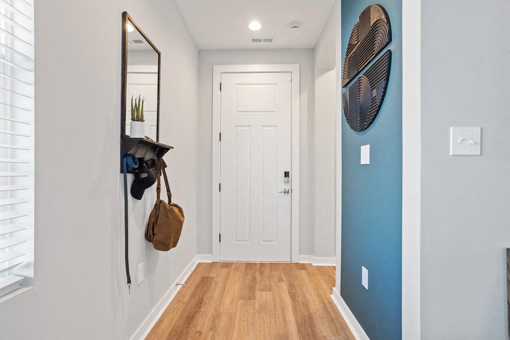 an entrance hall with overhead light, wood-style flooring, and a blue accent wall in a home at Sanctuary at Indian Creek
