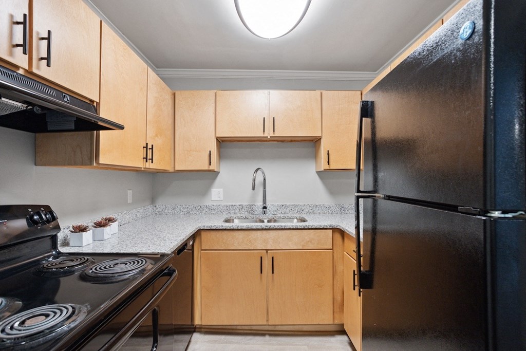 a kitchen with black appliances, wood cabinets, and granite countertops in a home at Mountainside Apartments