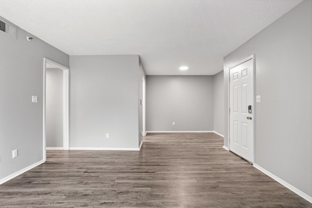 the spacious living room is empty and has a white door