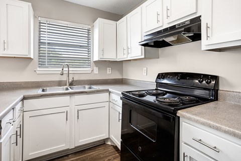 A black stove in a kitchen with white cabinets.