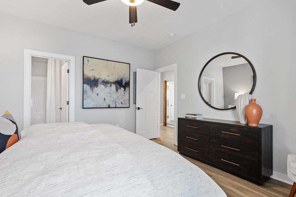 a spacious bedroom with an illuminated ceiling fan, model furnishings, and wood-style flooring