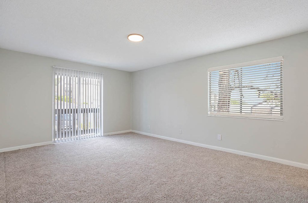 a spacious room with a large window and a sliding glass door to a private balcony