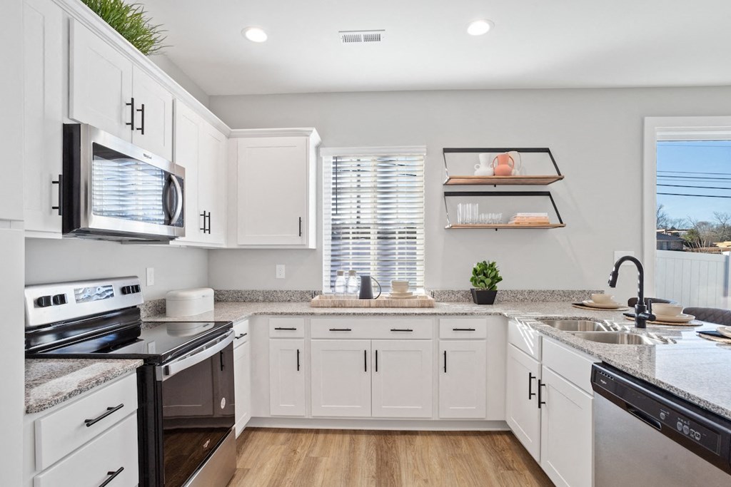 a large kitchen with white cabinets and stainless steel appliances in a rental home near Huntsville, AL