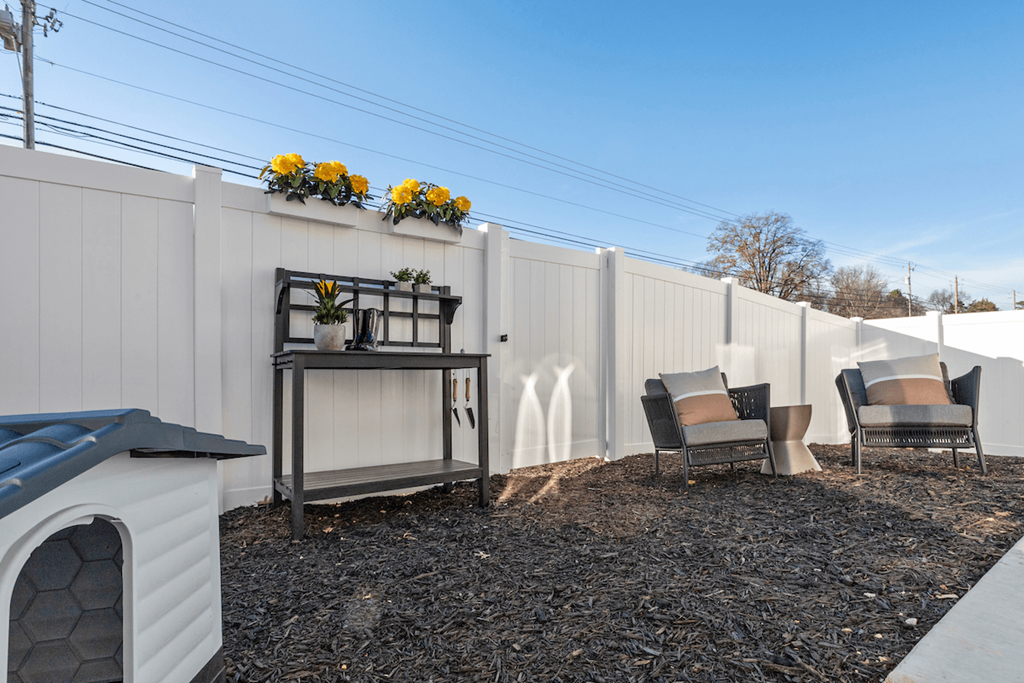 a fenced backyard with decor, a dog house, and flowers on the fence at Sanctuary at Indian Creek Rental Homes in Madison near Huntsville