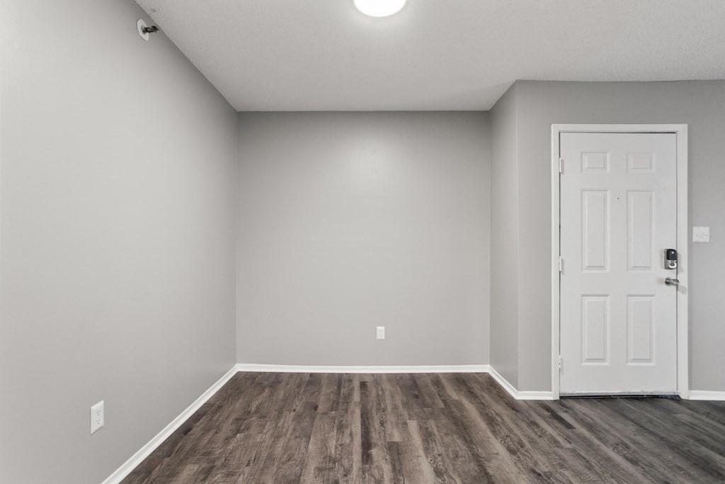 an empty living room with a white door and wood flooring