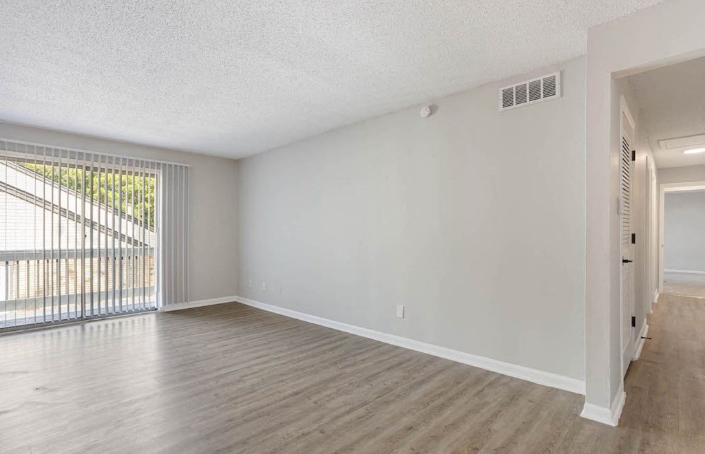 an apartment living room with wood-style flooring and ample natural light from the sliding glass doors