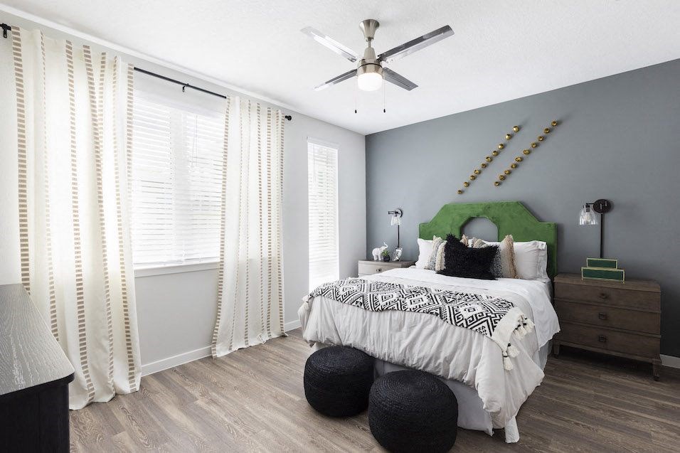 spacious bedroom with modern fan, wood-style floor, large window, and model decor at Residences at The Green