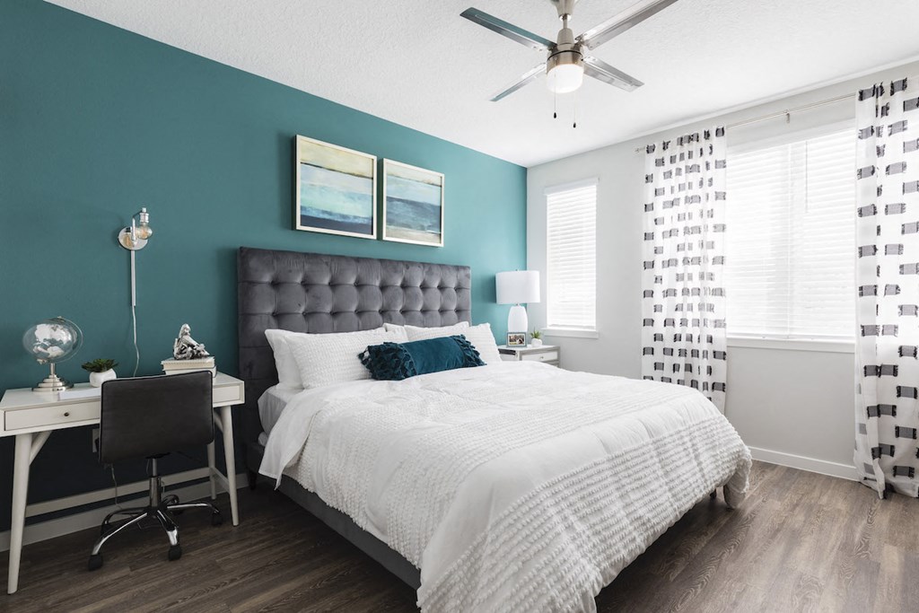 Bedroom with ceiling fan and large windows at Residences at The Green in Lakewood Ranch, FL