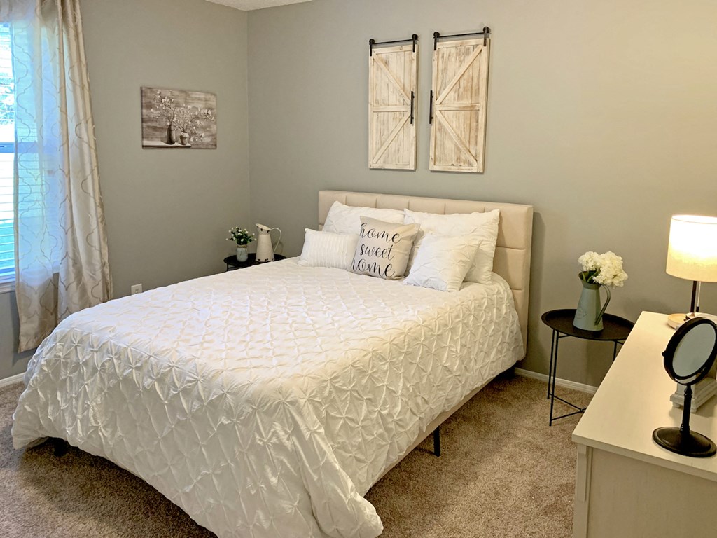 bedroom with large window, plush carpet, and model furnishings