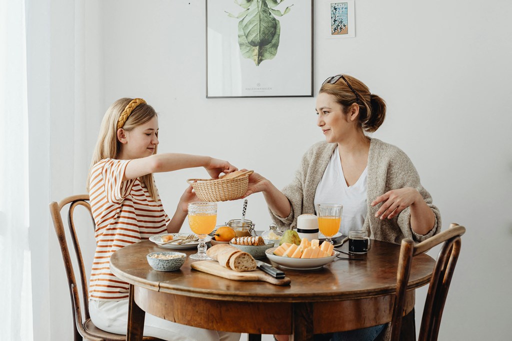 a mother and daughter sitting at a table eating breakfast