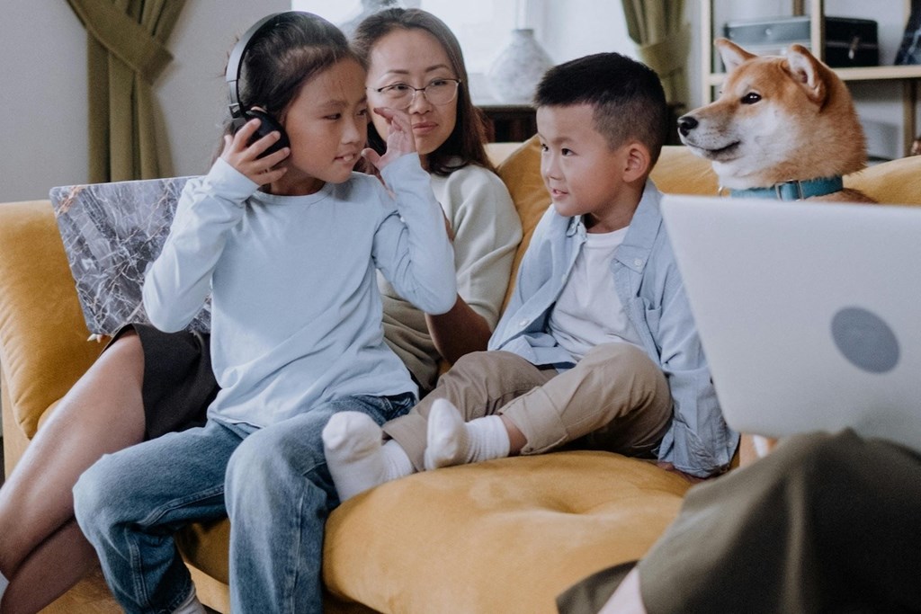 a family sitting on a couch talking on the phone and looking at a laptop