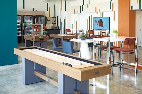 a game room with tables and chairs and a shuffleboard at Citizen Birmingham Apartments