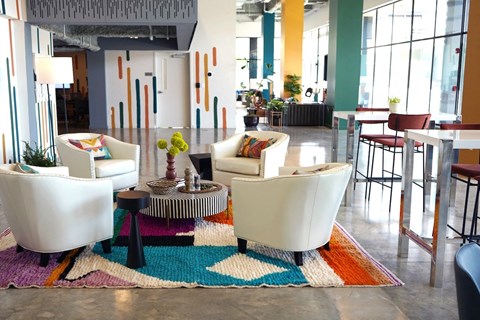 a living room with white furniture and a colorful rug at Citizen Birmingham Apartments