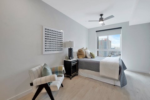 spacious studio with a large city view window, ceiling fan, and wood-style flooring