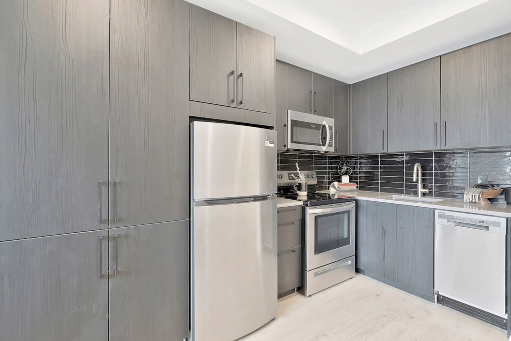 kitchen with ample cabinetry, stainless steel appliances, and wood-inspired flooring