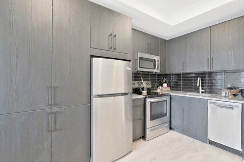 kitchen with ample cabinetry, stainless steel appliances, and wood-inspired flooring