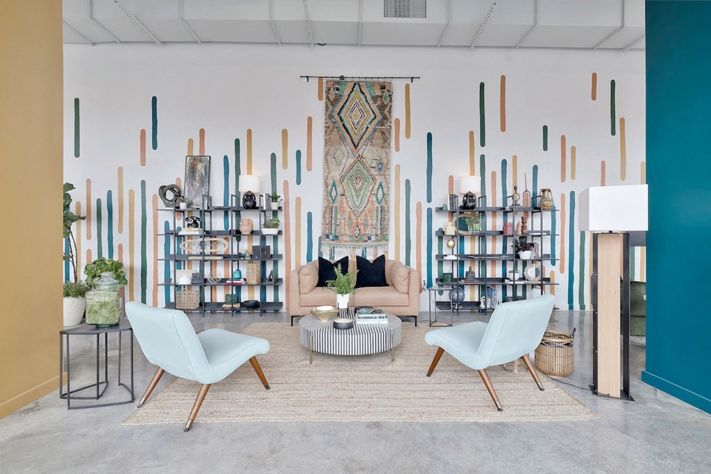 residential lounge on the ground floor with sofa, chairs, mural, and decor