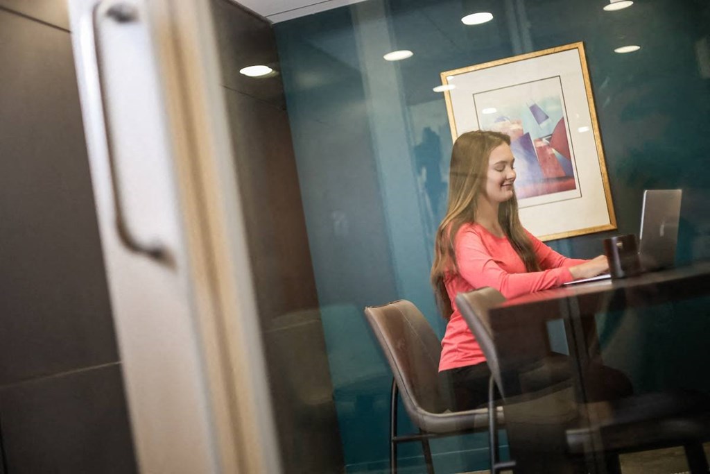 a woman sitting at a desk with a laptop in the micro office suite at Citizen Apartments