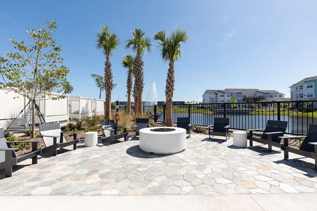 firepit with lounge chairs surrounded by trees and the pond at Lake Nona Concorde