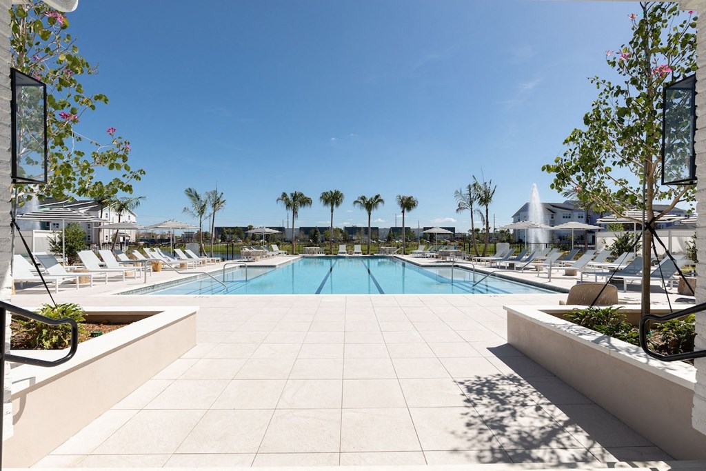 a swimming pool with chaise lounge chairs and trees at Lake Nona Concorde