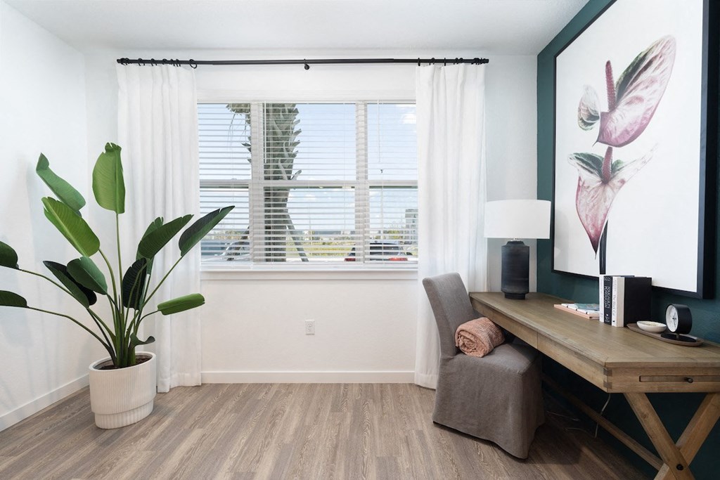 solarium with a large window, wood-style floors, and model decor