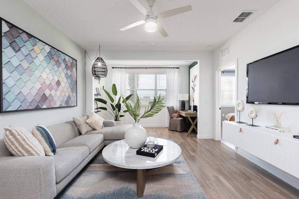 a living room and solarium with ceiling fan, wood-style floors, and model decor
