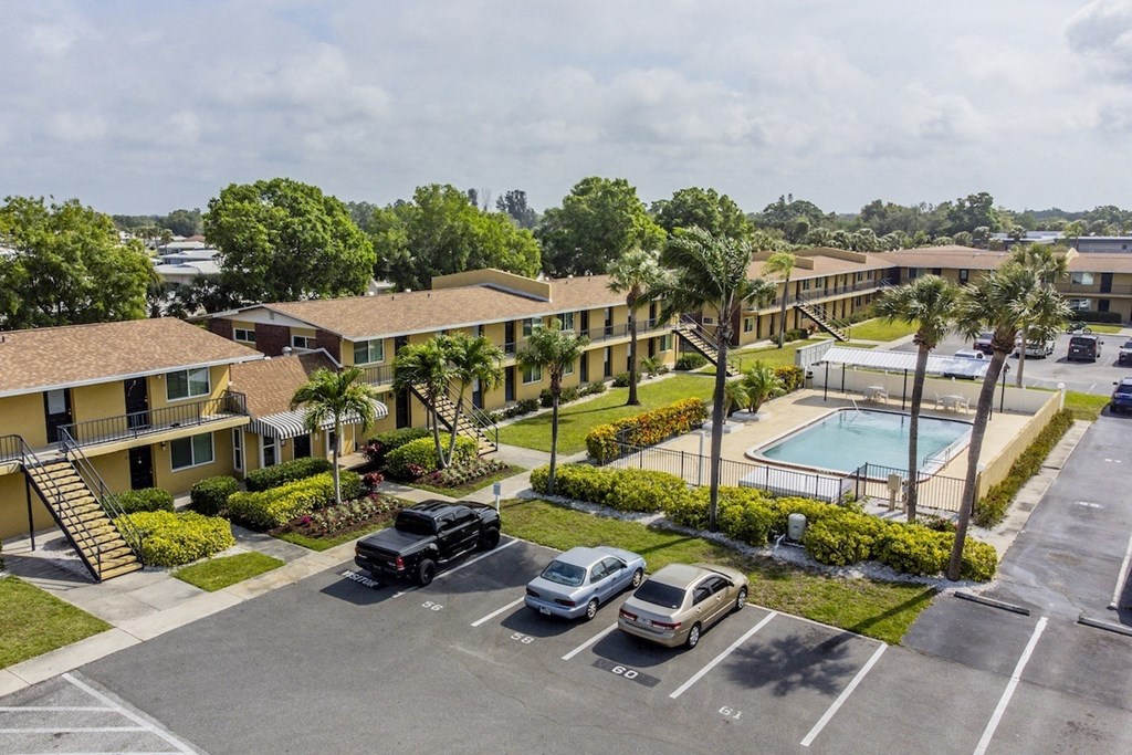 an aerial view of an apartment complex with a pool and parking lot