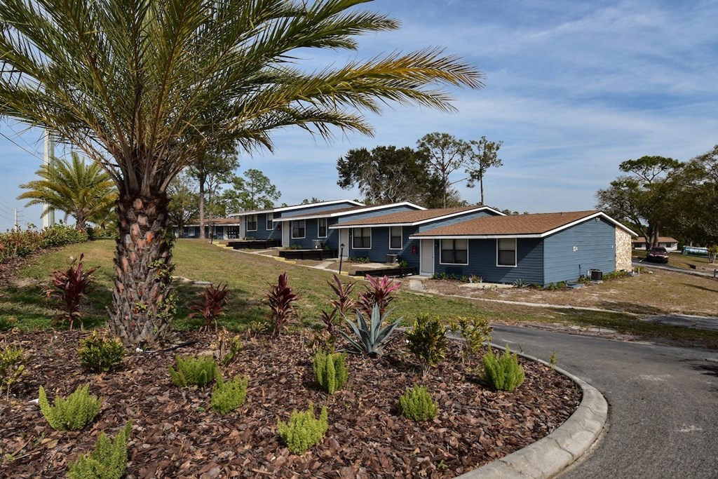 a row of blue bungalow apartments with palm trees at The Sands on Clearlake