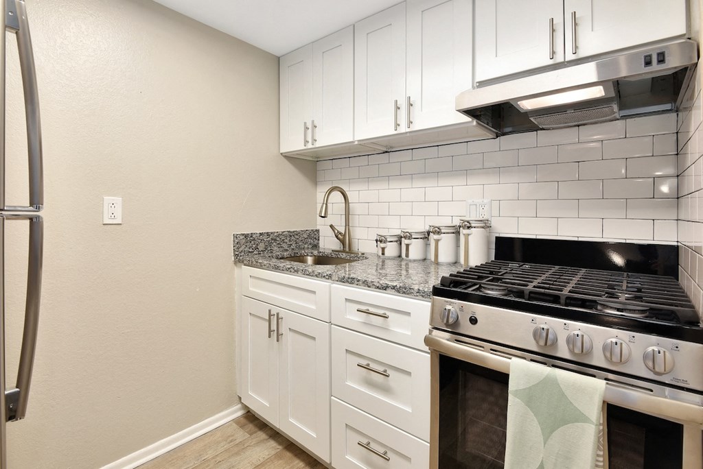 An apartment kitchen with stainless steel appliances and granite countertops at The Oasis Apartments in Daytona Beach, FL