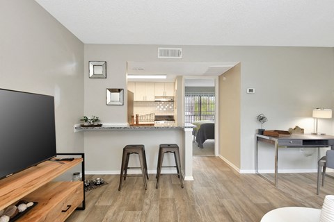 a living room with a kitchen in the background in The Oasis Daytona's model apartment