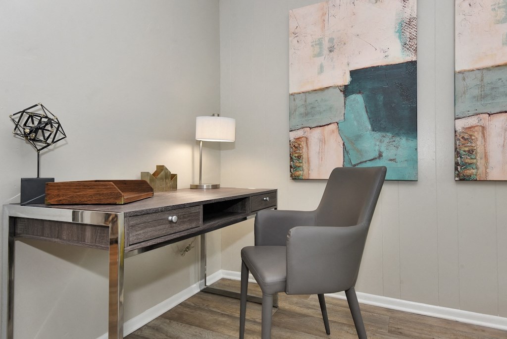 a desk with a chair and lamp in a room with paintings on the wall in The Oasis Daytona Apartment