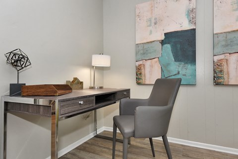 a desk with a chair and lamp in a room with paintings on the wall in The Oasis Daytona Apartment
