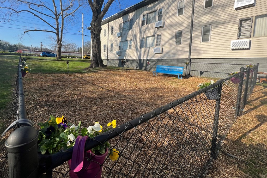 fenced dog park with flowers on the rails and a bench for people to use at The Flats at Jackson Square
