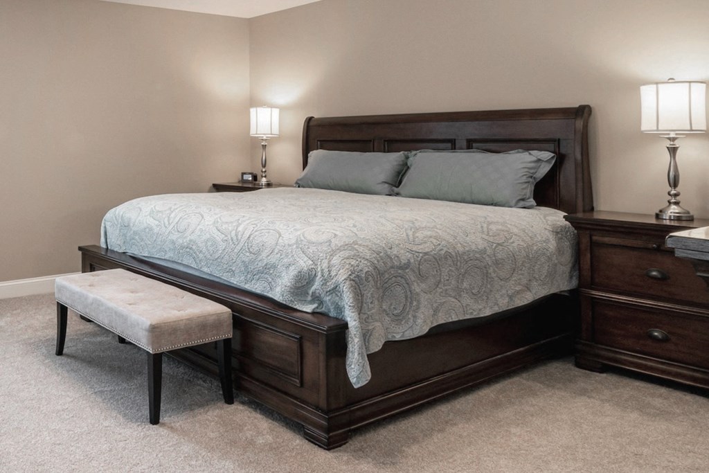 Eastland-Evansville-PG-8 a bedroom plush pillows on a bed and two night stands with lamps and a bench