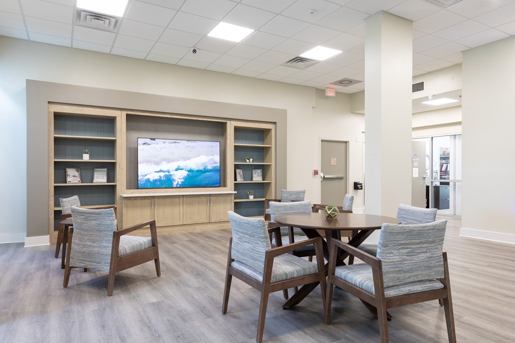 A conference room with a table, chairs, and a television on the wall.