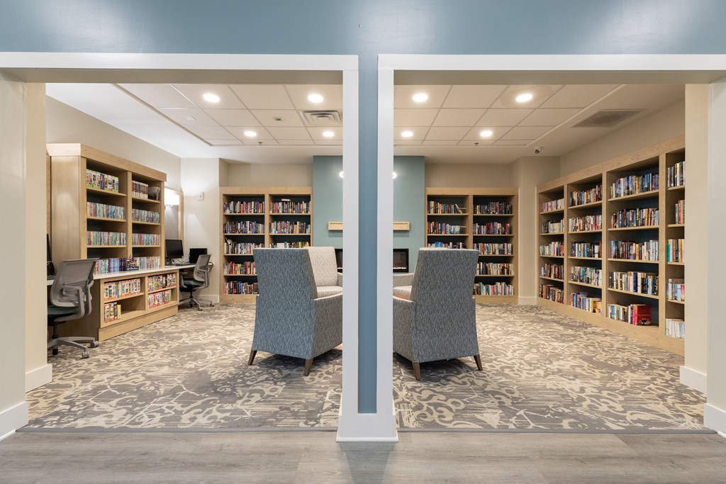 A library with two chairs in the middle of the room.