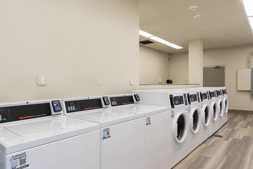 A row of white front load washing machines in a laundromat.