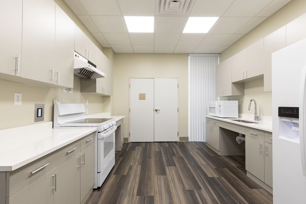 A kitchen with white appliances and wood floors.