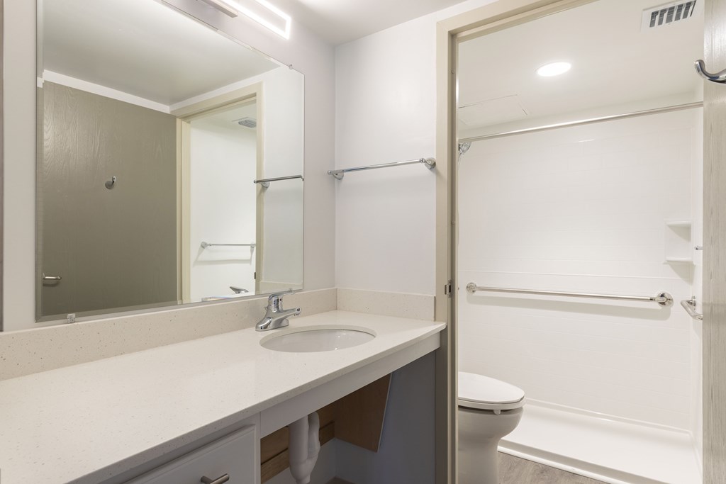 A bathroom with a sink, mirror, toilet and bathtub.