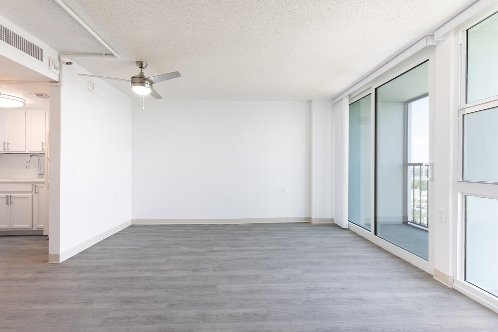 A room with a ceiling fan and a door leading to a kitchen.