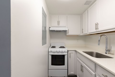 A white kitchen with a stove and sink.