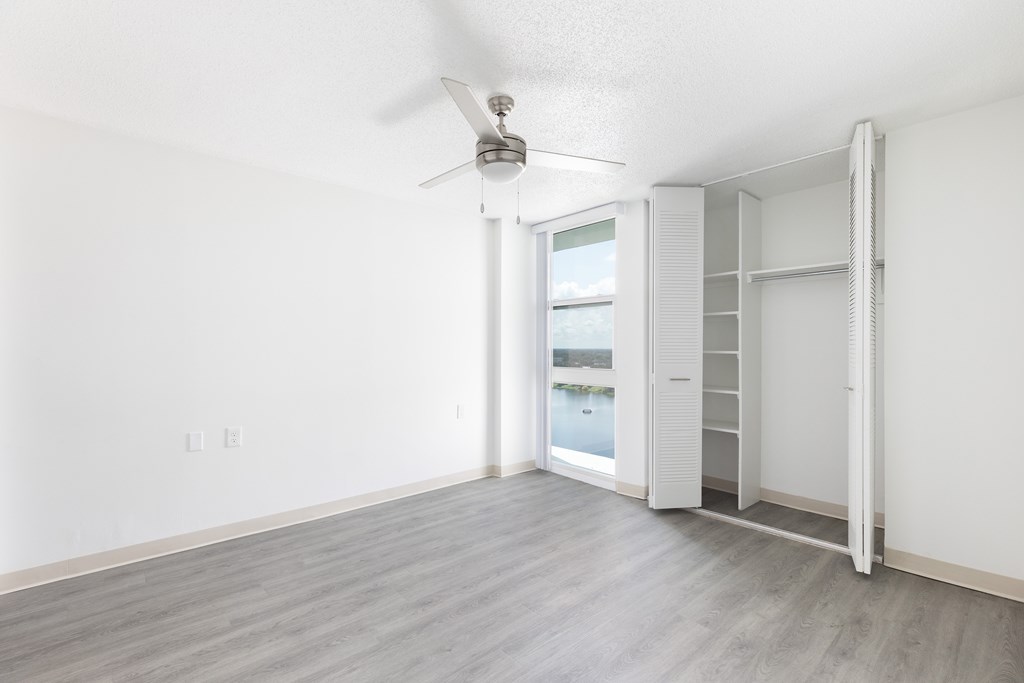 A room with a ceiling fan and a sliding door leading to a balcony.