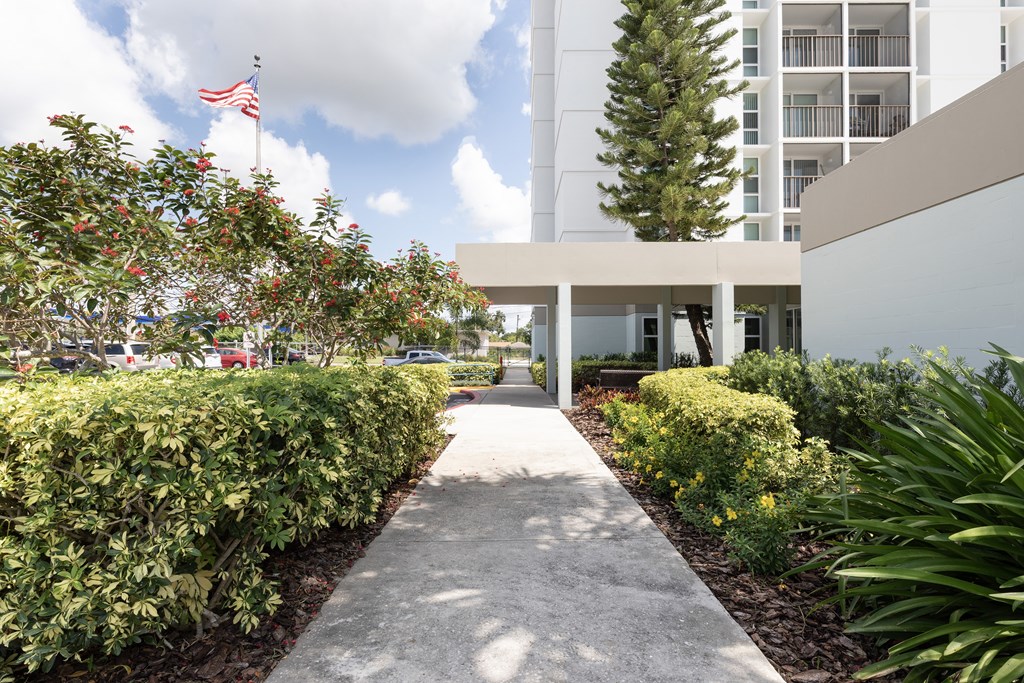 A pathway leads to a white building with a flag on top.