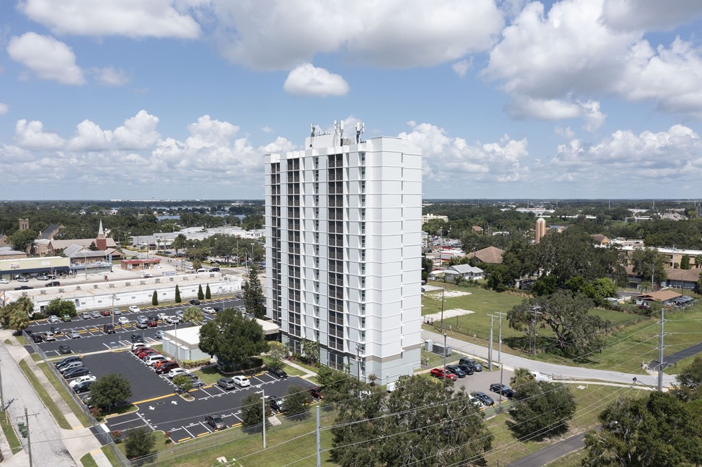 A tall white building with a parking lot in front of it.