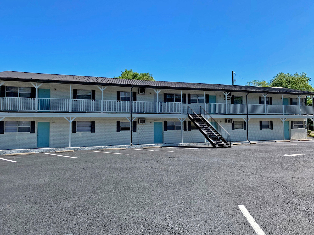 freshly painted apartment exterior with white brick and turquoise door