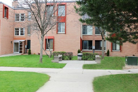 A red brick building with a tree in front.