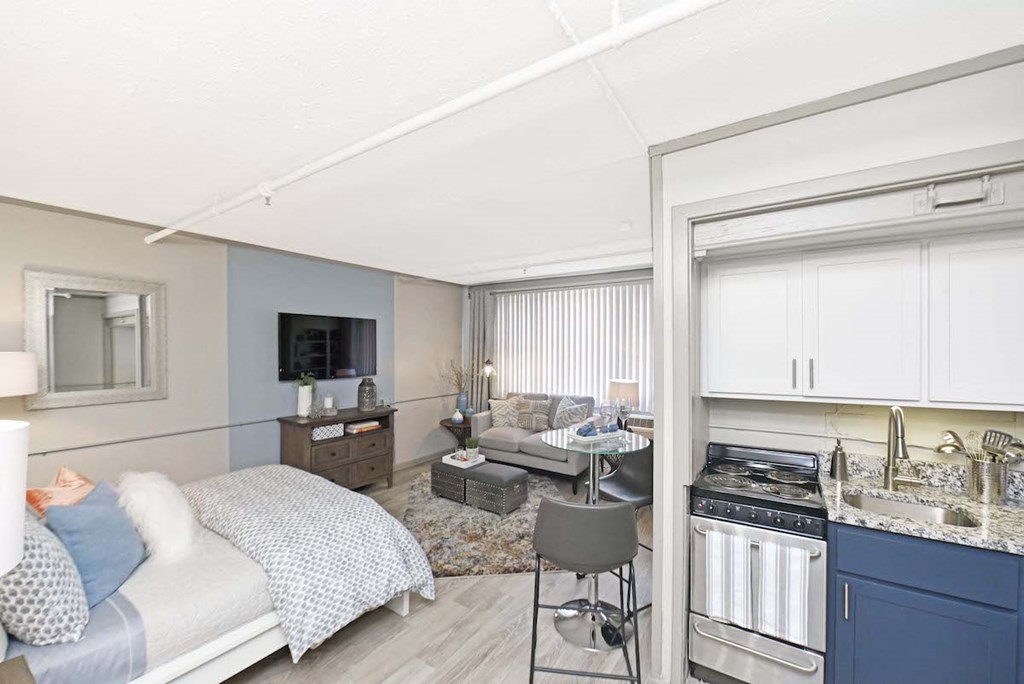 kitchen with stainless steel appliances, white and navy cabinets, and living space