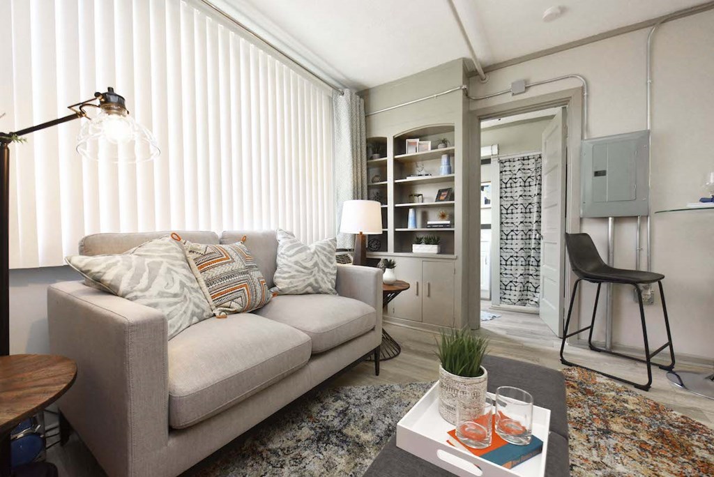 living room with built-in shelving, large window, and model furnishings